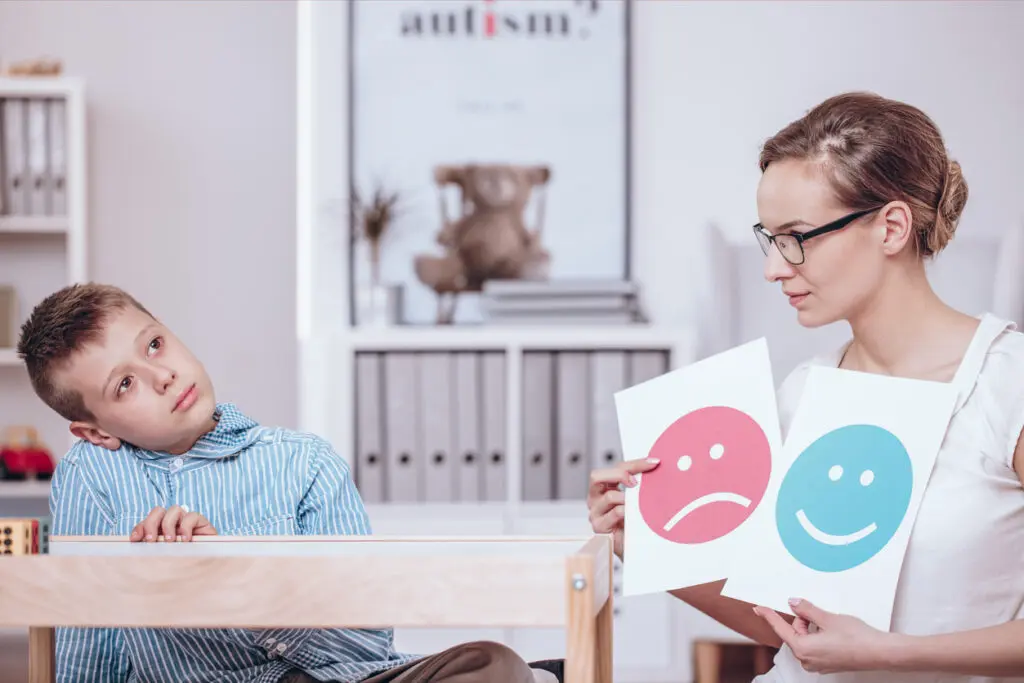 A medical worker uses pictures for autism therapy with a child.